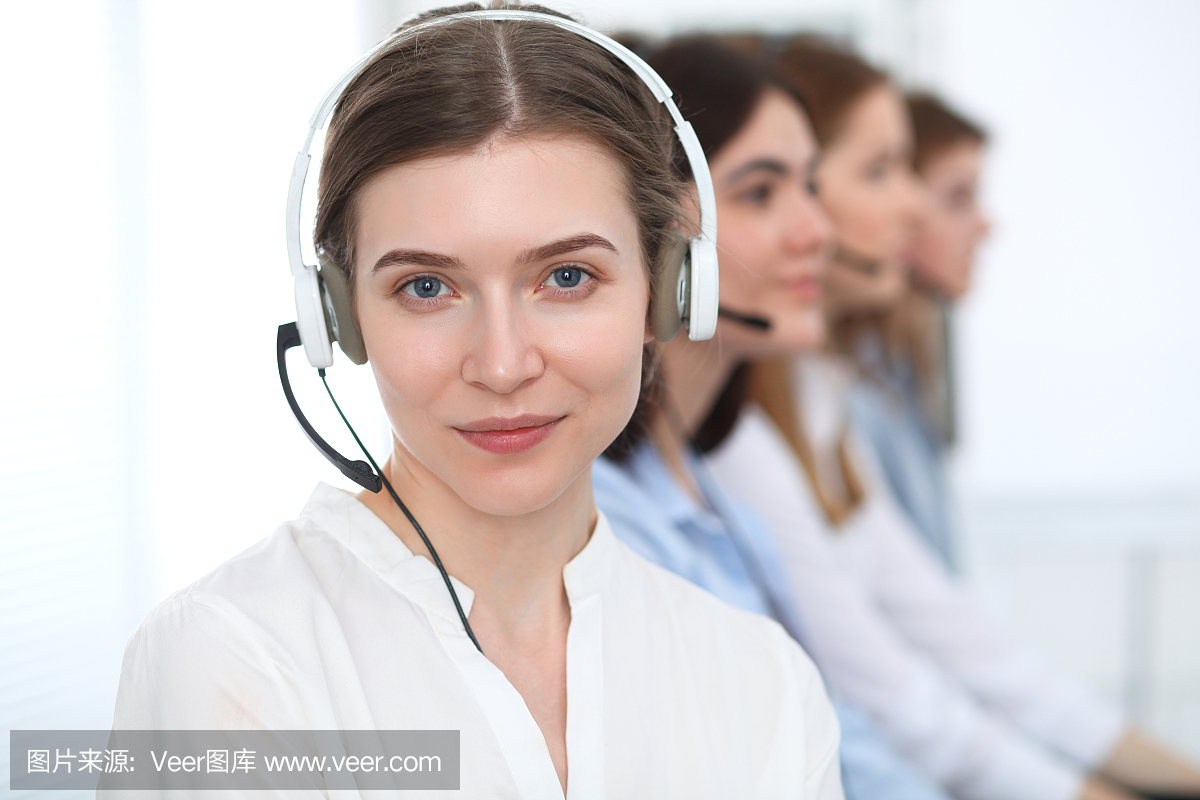 呼叫中心。美丽开朗微笑的操作员戴着耳机咨询客户。客户服务的经营理念。